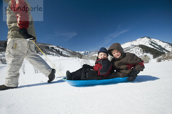 Vater zieht Kinder auf Schlitten durch den Schnee  fully_released