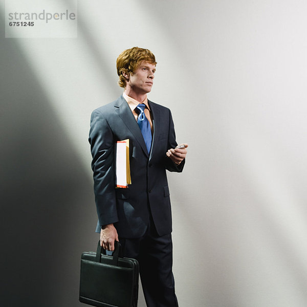 Businessman holding cell phone  files and briefcase