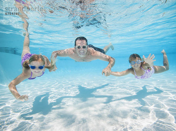 Father with two daughters (6-7 8-9) swimming underwater