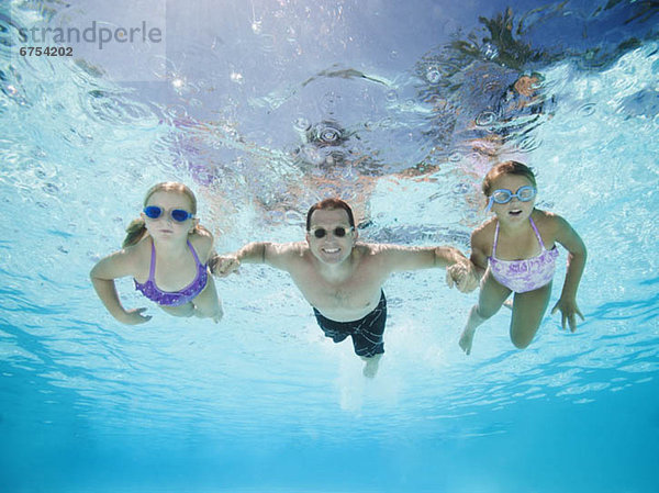 Father with two daughters (6-7 8-9) swimming underwater