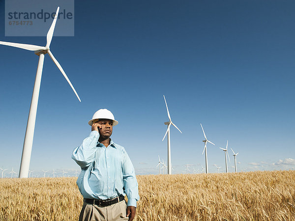 Vereinigte Staaten von Amerika USA Windturbine Windrad Windräder stehend frontal Ingenieur Weizenfeld telefonieren benutzt Handy