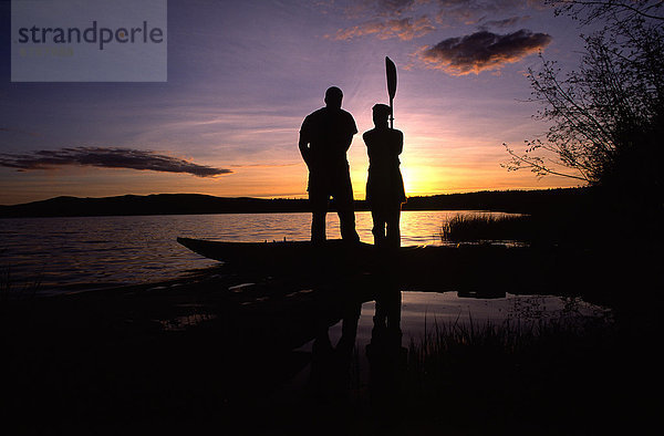 stehend  nebeneinander  neben  Seite an Seite  Sonnenuntergang  Silhouette  Kajak  Yukon