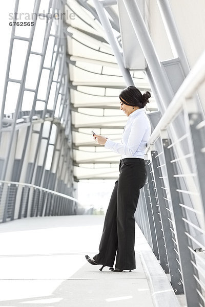 Young businesswoman on walkway  using cell phone