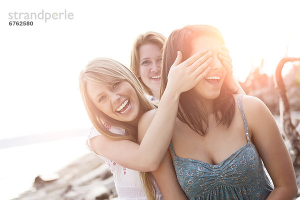 Three young women hanging out  covering eyes and laughing