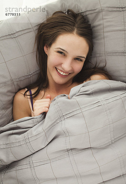 Portrait einer jungen Frau im Bett liegend