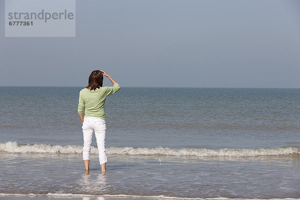 Frau am Strand mit Blick zum Meer