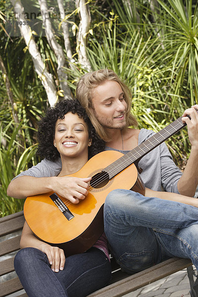 Young couple in park  man playing guitar