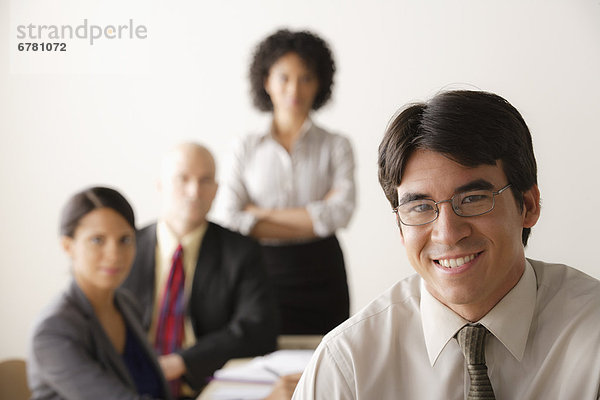 Young businessman looking at camera  business team in background