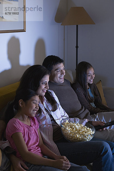 Family with two children (8-9  10-11) watching tv on sofa