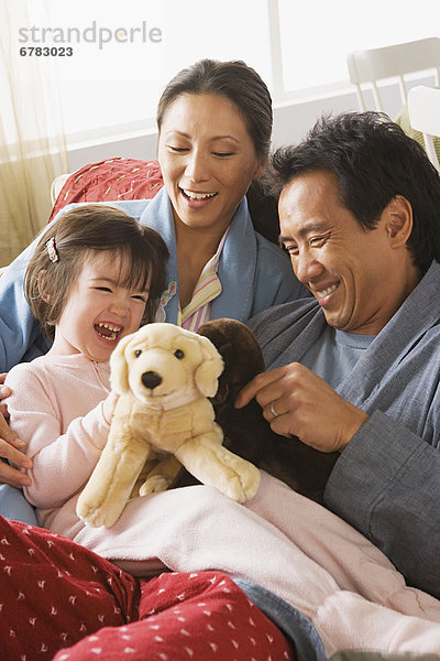 sitzend  Menschliche Eltern  Bett  Spielzeug  belegt  Tochter  spielen