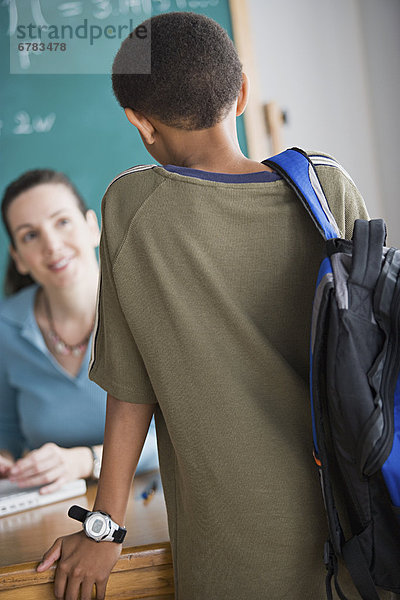 hinter  sitzend  Schreibtisch  sprechen  Lehrer  Grundschüler