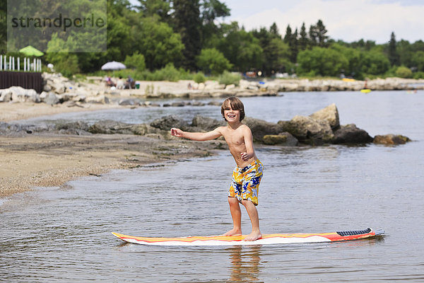stehend  lächeln  Junge - Person  Surfboard  Gimli  Winnipegsee  Kanada  Manitoba