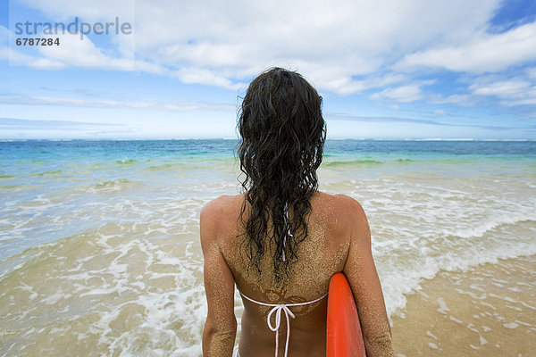 Hawaii  Kauai  Frau hält Surfbrett am Strand  Anzeigen von hinten.