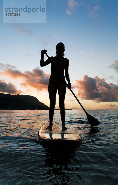 Hawaii  Kauai  Frau Stand up Paddeln im Ozean  schöne Sonnenuntergang.