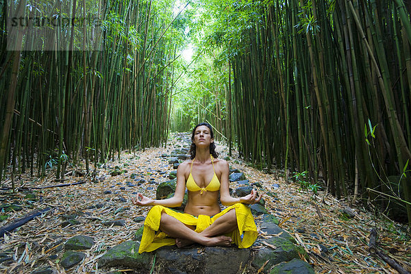 Hawaii  Maui  Kipahulu  Frau meditierend in Bambuswäldern.