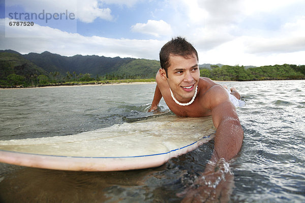 Hawaii  Oahu  Aina Haina  junger Mann Paddeln auf seinem Surfbrett im Wasser.