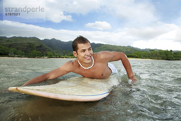 Hawaii  Oahu  Aina Haina  junger Mann Paddeln auf seinem Surfbrett im Wasser.