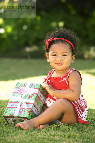 Hawaii  Oahu  Baby Mädchen hält Weihnachtsgeschenk.
