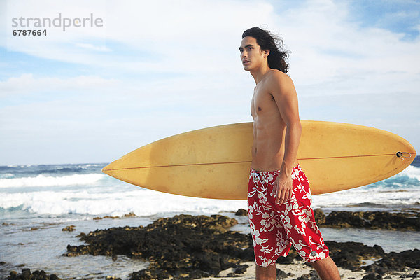 Hawaii  Oahu  junger Mann am Strand mit Surfboard.