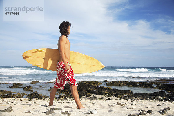 Hawaii  Oahu  junger Mann am Strand mit Surfboard.