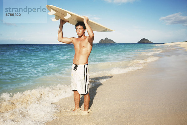 Hawaii  Oahu  junger Mann am Strand mit Surfboard.