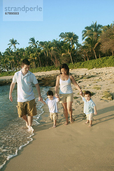 Hawaii  Oahu  North Shore  junge Familie hält hände Spaziergang am Strand entlang.