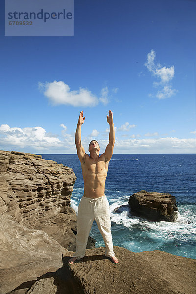 Hawaii  Oahu  Male tun Yoga auf felsigen Klippe.