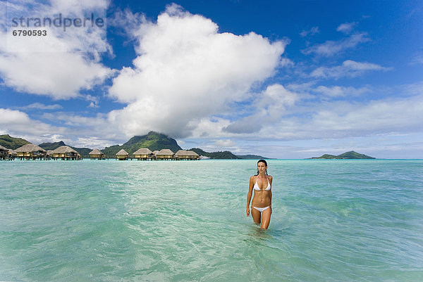 Französisch-Polynesien  Tahiti  Bora Bora  Frau im Ozean mit Bungalows im Hintergrund.