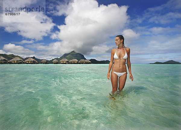Französisch-Polynesien  Tahiti  Bora Bora  Frau im Ozean mit Bungalows im Hintergrund.