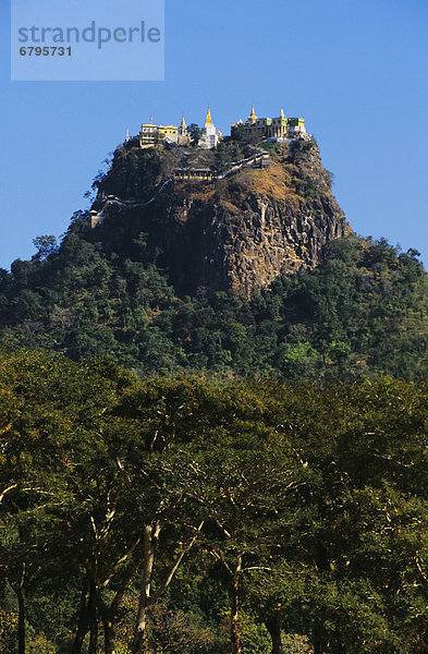 Burma (Myanmar)  Bagan  Mount Popo  temples on mountain top  trees in foreground.