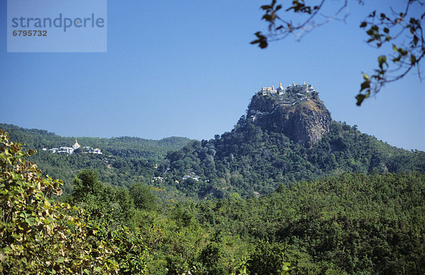 Burma (Myanmar)  Bagan  Mount Popa  temples on hillside  greenery in foreground.