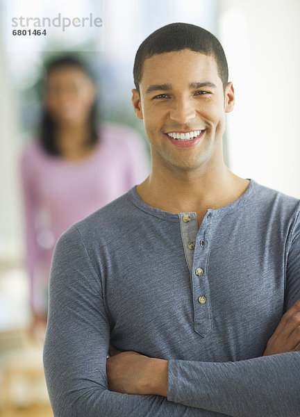 Portrait of man smiling  woman in background