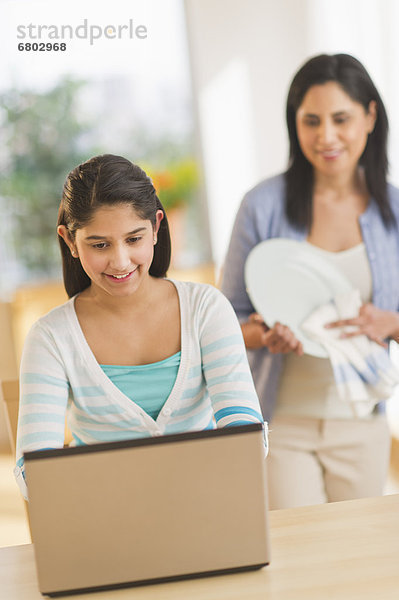 benutzen Notebook Wohnhaus 12-13 Jahre 12 bis 13 Jahre Mädchen Mutter im Hintergrund