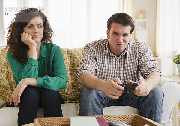 Couple sitting on sofa  man playing video game