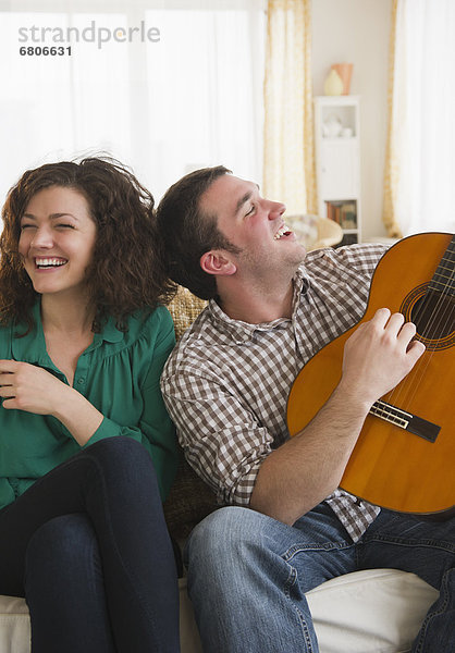 Couple sitting on sofa  man playing guitar