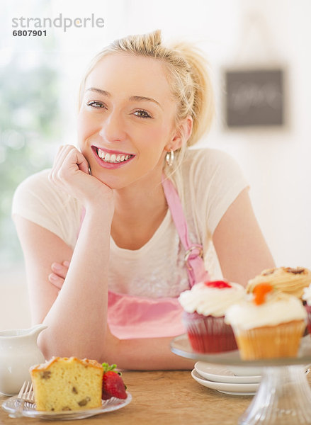 angelehnt junge Frau junge Frauen lächeln Kuchen Schürze Tisch