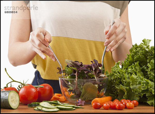 Junge Frau bereitet Salat zu