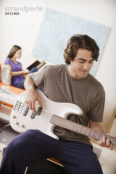 Young man playing electric guitar  young woman in background