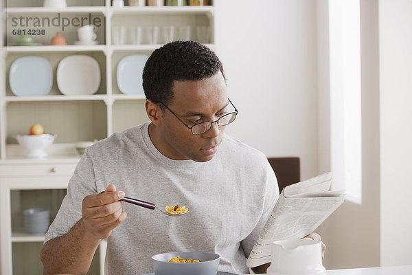 Mann Mittelpunkt essen essend isst Erwachsener Frühstück Zeitung vorlesen