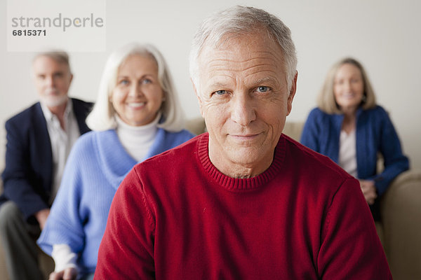 Two senior couples on sofa  smiling man in foreground