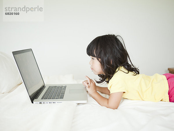 Girl lying down in bed  using laptop (4-5)