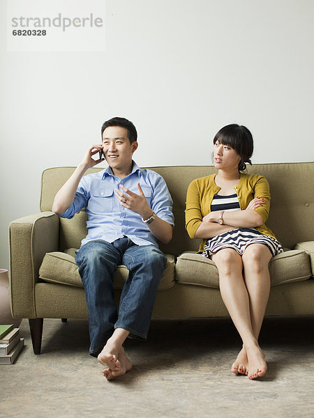 Young couple sitting on sofa  man talking via mobile