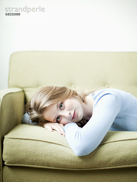 Portrait einer jungen Frau auf Sofa liegend