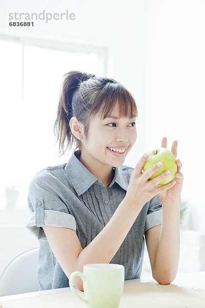 sitzend junge Frau junge Frauen halten Apfel Tisch