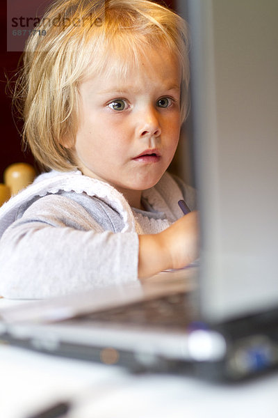 Blondes Mädchen schaut auf einen Laptop