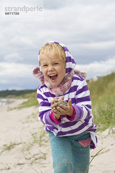 Fröhliches Mädchen spielt am Strand