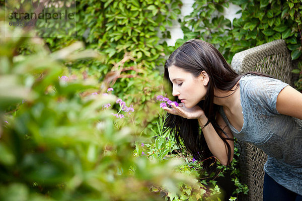 Junge Frau riecht Blume im Garten