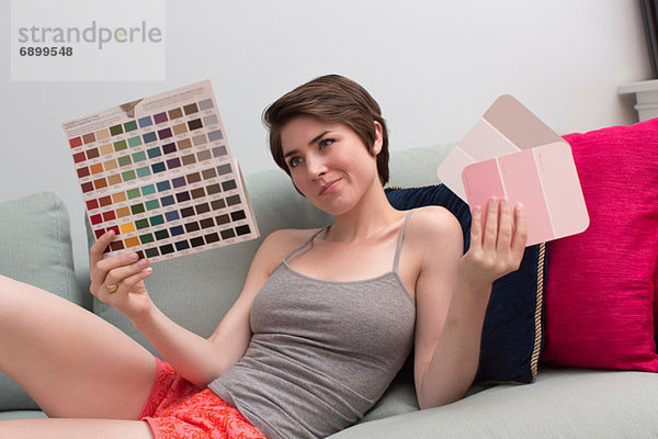 Junge Frau auf dem Sofa beim Betrachten von Farbmustern