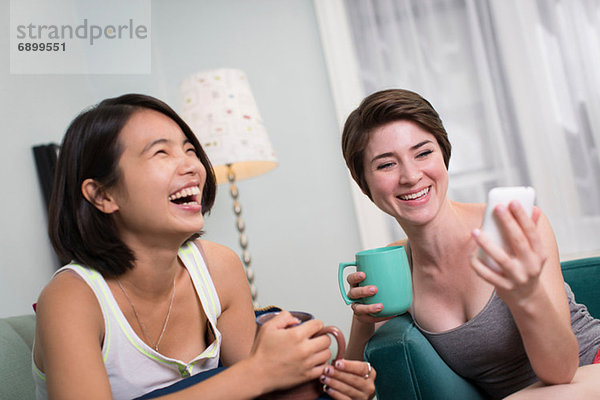 Junge Frauen  die auf das Smartphone schauen und lachen