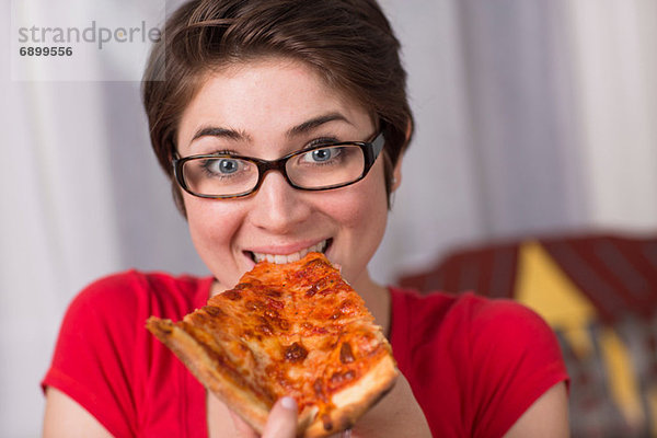 Junge Frau isst ein Stück Pizza.